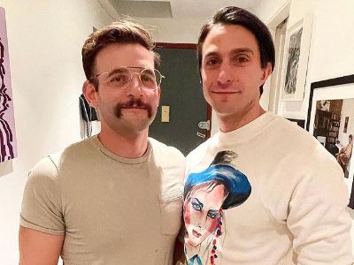 Gideon Glick is wearing a white tee with a picture of a girl on it, whereas, Perry Dubin is rocking a moustache and glasses.